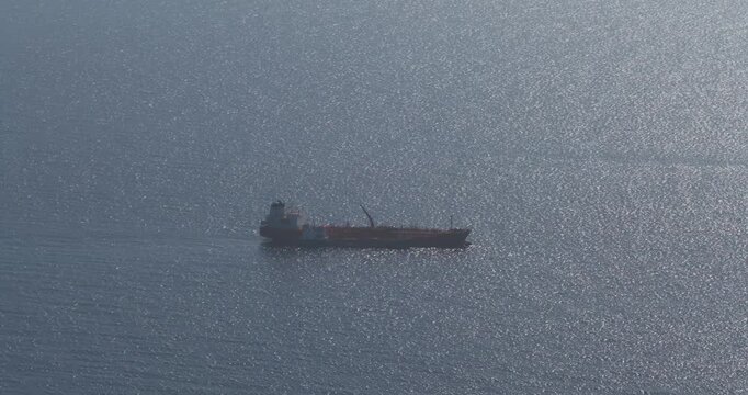 Aerial view of a ship sailing on the glittering sea, creating a beautiful contrast against the deep blue water, Munxar Path, Marsaskala, Malta.