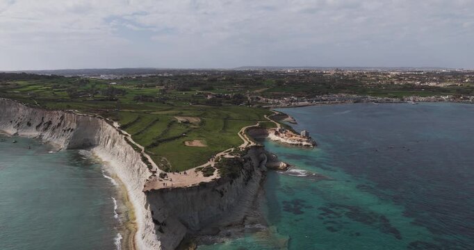 Aerial view of the rugged coastline where the white cliffs meet the turquoise sea in Munxar Path, creating a stunning contrast, Munxar, Marsaskala, Malta.