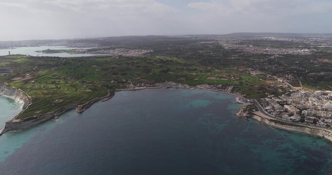 Aerial view of the rugged coastline with terraced fields meeting the turquoise waters of the Mediterranean Sea, Munxar Path, Marsaskala, Malta.