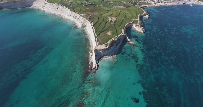 Aerial view of the dramatic white cliffs meeting the turquoise sea, creating a stunning contrast along the Munxar Path coastline, Munxar Path, Marsaskala, Malta.