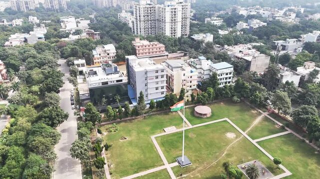 A towering Indian tricolour rises above a manicured neighborhood park in Greater Noida, surrounded by walkways, lawns, and quiet residential streets.