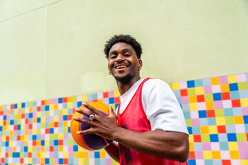 Smiling young man playing basketball on colorful court