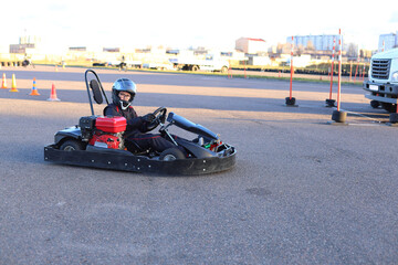 A young racer in full gear steers a go kart on an outdoor track, focused, poised, and ready for action at golden hour.