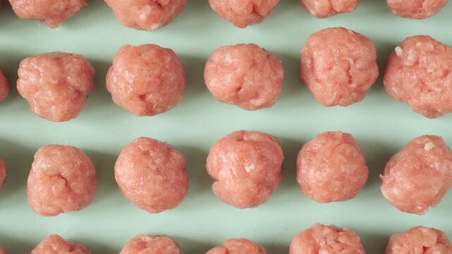 Rows of fresh uncooked meatballs moving on a production line creating a seamless looping patternю