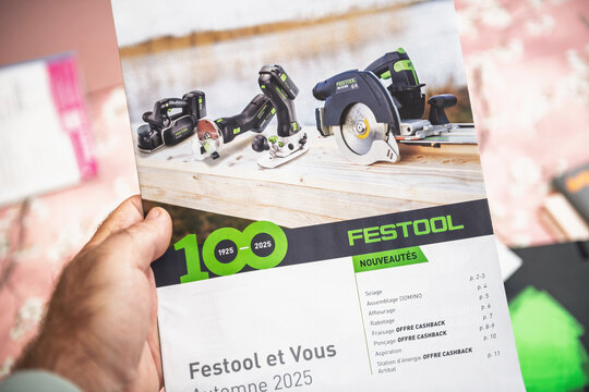 Paris, France - Sep 4, 2025: A hand holds a Festool Autumn 2025 brochure showing new cordless power tools on a wooden plank with the brand s green centenary logo and product index