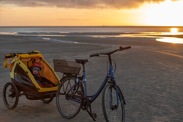 Fototapeta premium Fahrradtour an der Nordsee auf dem Strand, hier auf Borkum im Sonnenuntergang