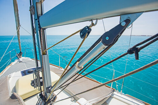 Landscape view from bow of luxury sailing boat yacht with detail of main mast and rigging showing blue ocean background