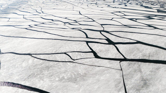 Aerial view of fractured ice, a mosaic of white and dark lines creating a stark contrast in the winter landscape. Superior, Wisconsin, USA.