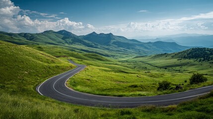Winding road across green hills and mountain valley