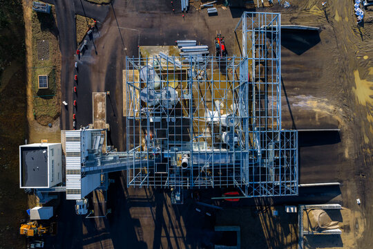 Aerial view of a metal framework structure casting long shadows across the landscape, highlighting the contrast between construction and nature, La Roche-Jaudy, Brittany, France.
