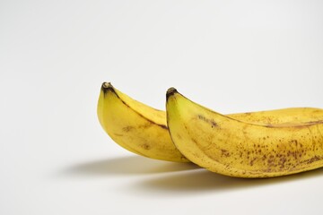 Close-up of two ripe bananas with yellow peel on white background