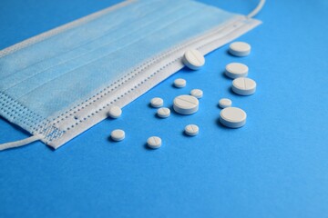 Medical mask and pills on a blue background