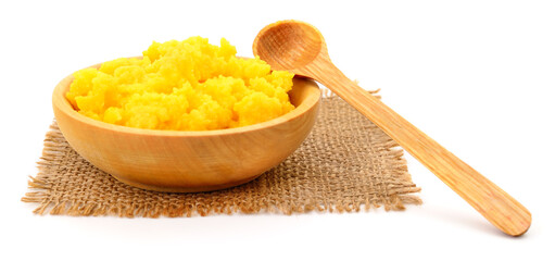 Wooden bowl with yellow ghee butter and spoon isolated on white background