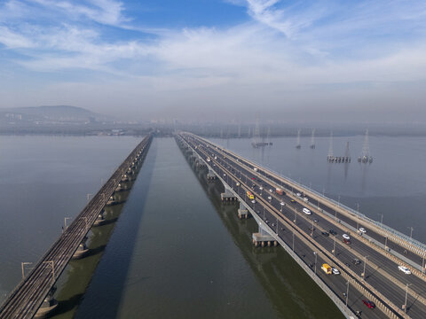 Aerial view of the Vashi Bridge stretching across the Thane Creek, with cars traversing the bridge's expanse, and the railway bridge running parallel, Vashi, Maharashtra, India.