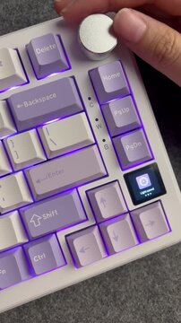 Close up of a hand rotating a silver metal knob on a mechanical keyboard with purple RGB light.