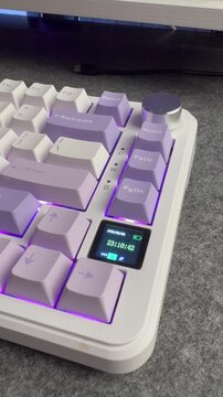 Side view of a white mechanical gaming keyboard with purple LED backlit on a grey desk mat.