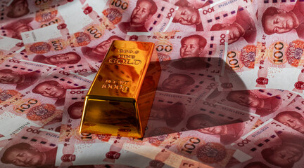 A gold bar against a background of 100 Chinese yuan bills © Max Zolotukhin