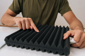 Person checking soundproof foam panel, doing quality check before installing acoustic insulation,...