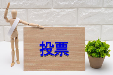 タスキを掛けた選挙の候補者と投票を促す看板