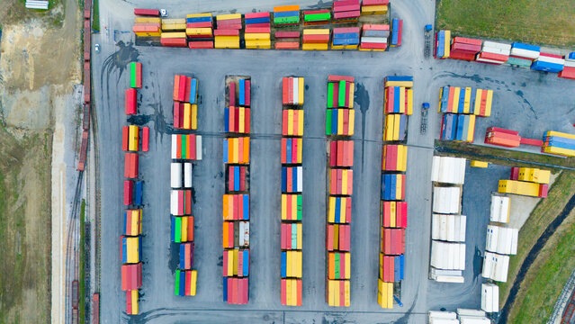 Aerial view of a vibrant array of cargo containers, stacked in neat rows, creating a colorful tapestry against the muted tones of the surrounding landscape, Sremska Mitrovica, Vojvodina, Serbia.
