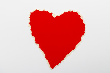 Bright red heart shape made from torn paper on a white background showing a simple design element