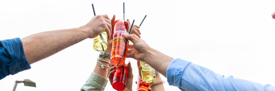 multiracial group friends having fun in park holding cocktail in hand - Happy people toasting cocktail glasses sitting at bar table - Cheerful friends enjoying happy hour at pub restaurant balcony