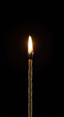 A close-up shot capturing a slender, glowing wick with a small, steady golden flame centered in the frame, providing warm ambient light ,relaxation ,source ,devotion