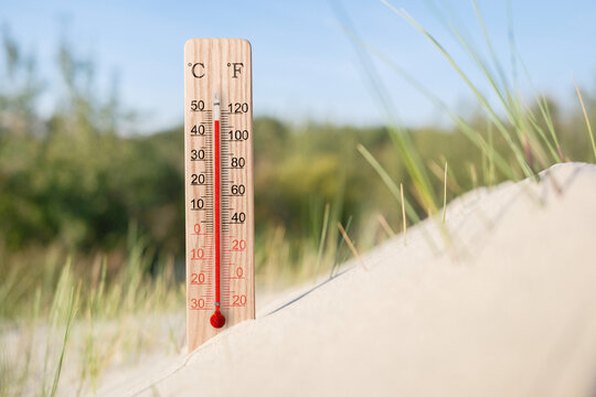Hot summer day. Celsius and fahrenheit scale thermometer in the sand. Ambient temperature plus 46 degrees