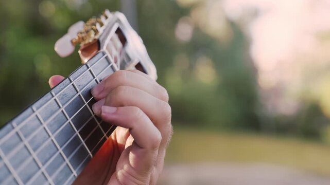 Close-up of the musician's playing hands.  The guitarist plays the guitar. Professional guitarist plays guitar outdoors. Musician plays a classical guitar in the park.