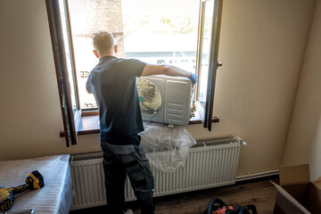 Master in black shirt is installing outer block air conditioner. Split system