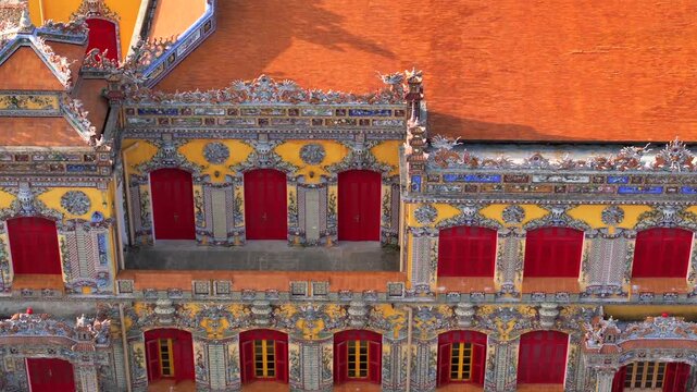 Kien Trung Palace in Hue Imperial City with a vibrant yellow facade, red shutters and roof details. Aerial Drone Shot