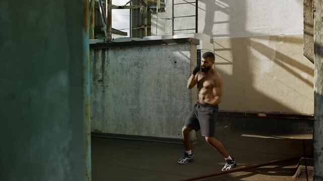 Black male fighter practicing boxing movements and combos on urban rooftop