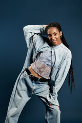 Fashionable young woman poses confidently in stylish denim against a trendy blue backdrop