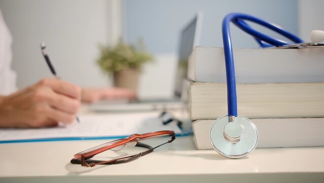 Medical student writing research with stethoscope and textbooks representing healthcare education, diligent study, and preparing for a career in medicine, becoming a doctor