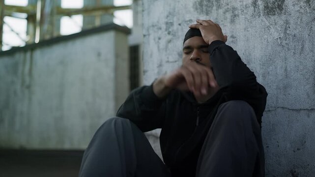 Unhappy African American man sitting on rooftop, thinking about family problems