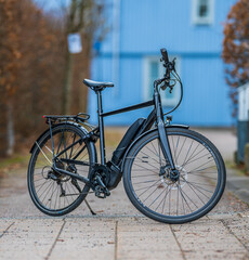 Modern black electric commuter bicycle parked in quiet suburban street.