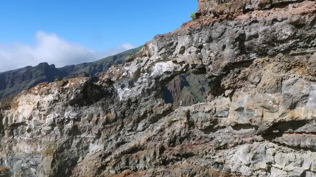 Hiking couple sitting inside El Bujero rock cave overlooking Los Gigantes cliffs and Masca Valley in Tenerife