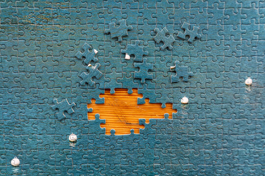 Blue jigsaw puzzle with missing piece revealing wooden background. Concept of problem solving, incomplete project, solution, strategy, business challenge and creativity.