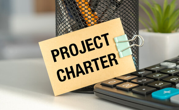 Project Charter blank sheet of paper on a notepad near the calculator. Business concept.