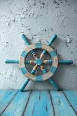 An old wooden steering wheel near a white rough plastered wall