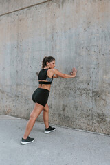 Fototapeta premium Young Hispanic woman stretching and exercising in sportswear outdoors in urban area at city