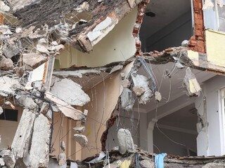 Exposed Rebar and Concrete Hanging from Partially Demolished Building. Dangerous Demolition Scene with Swinging Rebar and Rubble. Collapsed Structure with Hanging Metal and Concrete Fragments.