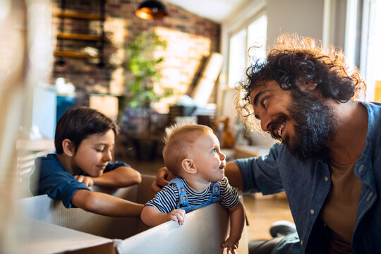 Father and children playing in moving boxes at home