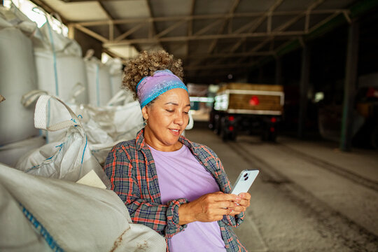 Female farm worker using smartphone in warehouse