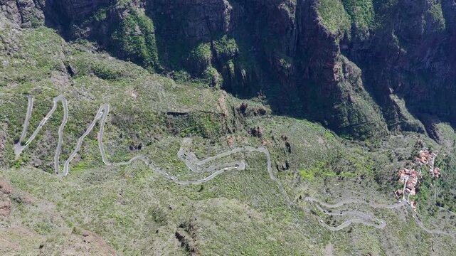 Cinematic aerial of the winding mountain road switchbacks leading to Masca village in Teno Rural Park Tenerife