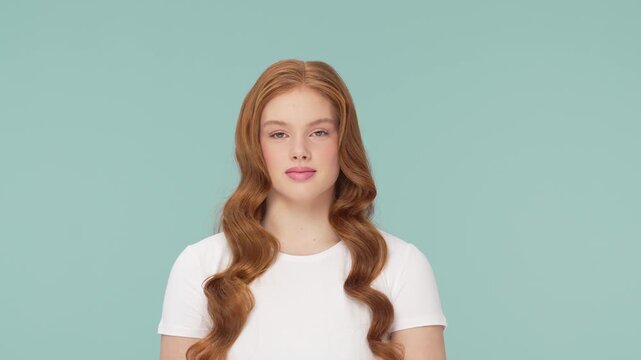 Beautiful teenage redhead girl posing in studio. Female of cute female teenager over bright solid background. Close-up face of young Caucasian woman.