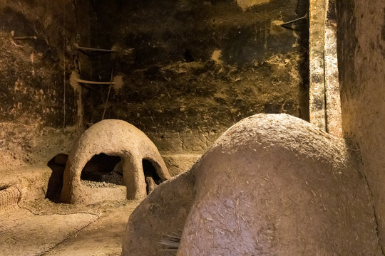 Interior view of a room with mud structures, possibly ovens or storage, in a dimly lit space. Kasbah Amridil,Marrakech,Morocco