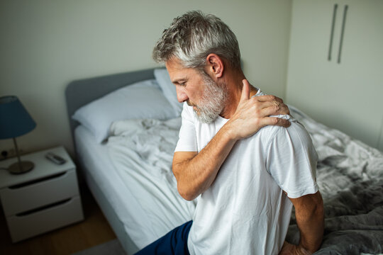 Older man with shoulder pain in bedroom