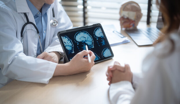 Doctor explaining brain MRI scan results on digital tablet.