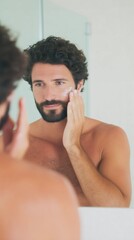 Man applying face cream in the bathroom. Young male taking care of skin, self-care and morning routine in home. Grooming for men.